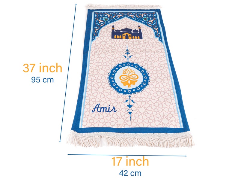 May include: A prayer rug, 37 inches long and 17 inches wide, featuring a mosque design and geometric patterns. The rug has a blue border and fringe, with the name "Amir" printed on it. The central design includes a gold and blue emblem.