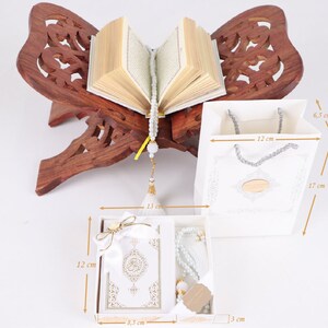 K&ouml;nnte beinhalten: Wei&szlig;e Geschenkbox mit einem wei&szlig;en Gebetsteppich, einer wei&szlig;en Gebetsperlenkette und einer wei&szlig;en Geschenkt&uuml;te. Die Box ist 8,5 cm breit, 12 cm hoch und 3 cm tief. Die Tasche ist 12 cm breit, 17 cm hoch und 6,5 cm tief.