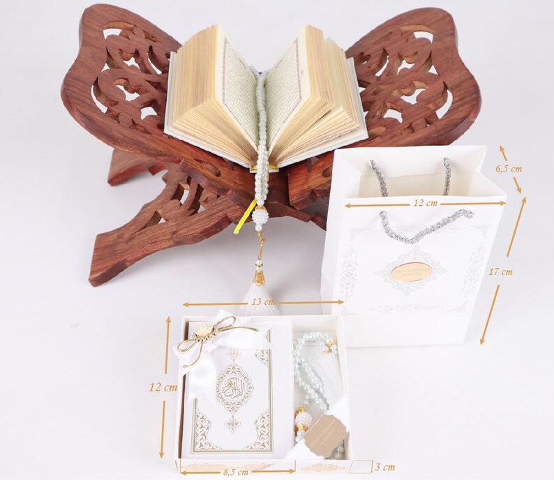 K&ouml;nnte beinhalten: Wei&szlig;e Geschenkbox mit einem wei&szlig;en Gebetsteppich, einer wei&szlig;en Gebetsperlenkette und einer wei&szlig;en Geschenkt&uuml;te. Die Box ist 8,5 cm breit, 12 cm hoch und 3 cm tief. Die Tasche ist 12 cm breit, 17 cm hoch und 6,5 cm tief.