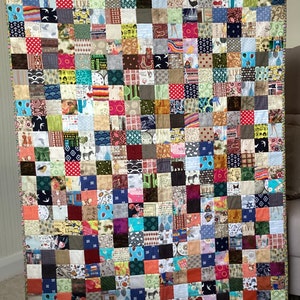 May include: A colourful patchwork quilt made of many different fabric squares. The quilt is made in a variety of colours, including red, blue, green, yellow, and brown. The quilt is made in a variety of patterns, including polka dots, stripes, and floral prints.