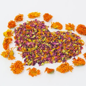 May include: Dried flower petals in a heart shape, surrounded by orange flower heads on a white background.