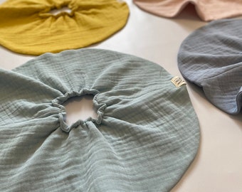 May include: A collection of six round, ruffled fabric circles in various colors, including light blue, yellow, beige, light pink, gray, and brown. The fabric is soft and textured, with a gathered edge.