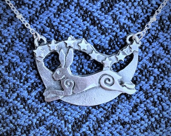May include: A silver necklace with a crescent moon pendant featuring a stylized rabbit and stars.