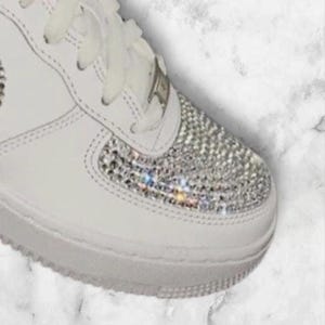 K&ouml;nnte beinhalten: Wei&szlig;e Lederschuhe mit wei&szlig;en Schn&uuml;rsenkeln und einer glitzernden, mit Kristallen besetzten Zehenkappe.