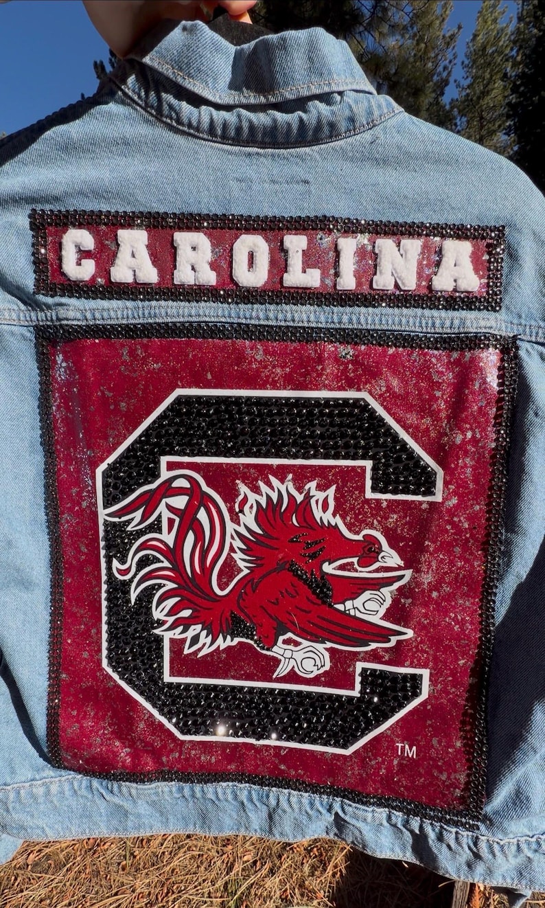 Custom Carolina Gamecocks game day denim jacket with garnet and black rhinestone details and a large Carolina logo patch.