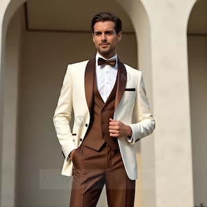 May include: A cream-colored tuxedo with a brown satin lapel, vest, and trousers. The suit includes a white dress shirt and a brown bow tie. The image shows a man wearing the formal attire.