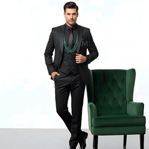 May include: A three-piece black suit with a black tie and a green vest. The suit is paired with black dress shoes. A green armchair is next to the suit.