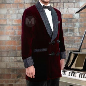 May include: A burgundy velvet blazer with a black satin shawl collar and quilted lining. The blazer has a double-breasted closure with decorative buttons and a black bow tie.