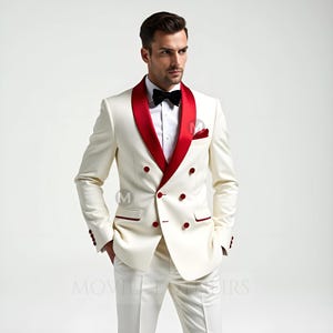 May include: A cream-colored double-breasted suit with a red satin lapel and matching red buttons. The suit includes a black bow tie and a red pocket square. The suit is paired with white pants.