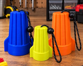 May include: Three oversized, ribbed, rocket-shaped wire connectors in blue, yellow, and orange. Each connector features a black cord with a sliding toggle attached to the top, allowing for easy handling and organization of these large electrical components.