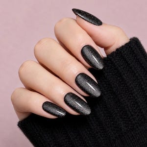 May include: Oval-shaped fingernails featuring a glossy black base coat with a subtle magnetic cat-eye effect that creates a shimmering silver-toned streak across the center of each nail, set against a black ribbed knit fabric sleeve.