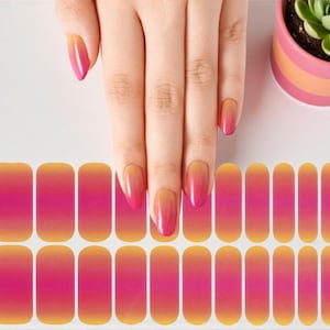 Peut inclure: Une main avec de longs ongles peints dans un dégradé de jaune à rose, avec des enveloppes d'ongles assorties. Les enveloppes d'ongles sont disposées en rangées, avec le même dégradé de couleurs. Un petit pot de succulente est en arrière-plan.