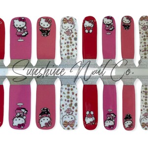 May include: A set of 10 Hello Kitty nail wraps featuring various designs, including Hello Kitty holding a heart, Hello Kitty in a dress, and Hello Kitty with a bow. The nail wraps are on a clear sheet with a silver glitter background and the text "Sunshine Nail Co."