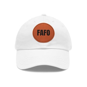 Puede incluir: Gorra de béisbol blanca con un parche de cuero marrón que dice "FAFO" en letras negras.