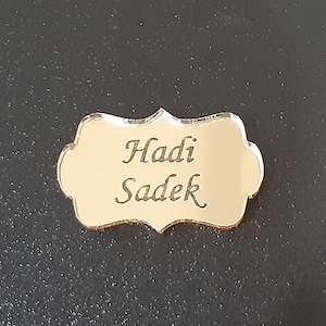 Peut inclure: Plaque en miroir doré avec le nom "Hadi Sadek" gravé dans une police d'écriture cursive décorative.