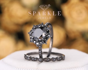May include: Black diamond engagement ring set with a halo setting and a matching band. The ring is set in black rhodium plated silver.