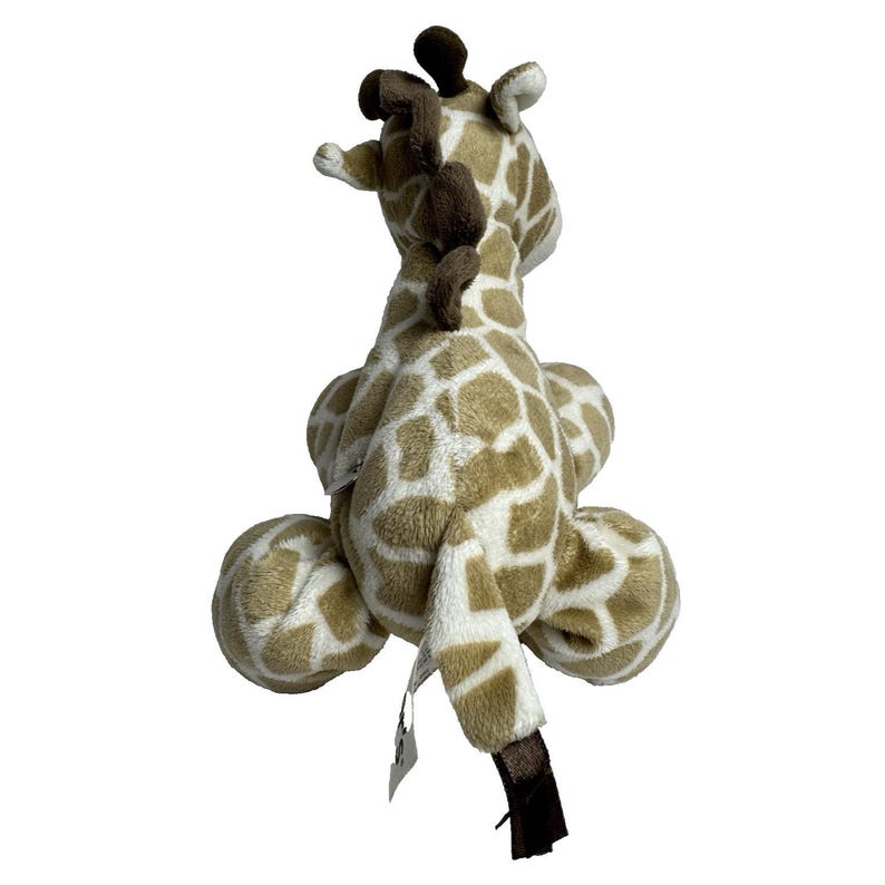May include: A plush giraffe toy with brown spots on a white background. The giraffe is sitting with its legs tucked under its body and its head tilted back. The giraffe has a brown tail with a black tip.
