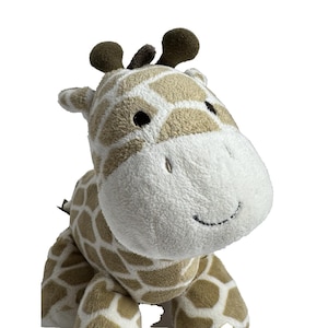 May include: A plush brown and white giraffe toy with a white face and black eyes. The giraffe has a brown and white patterned body and a brown nose.