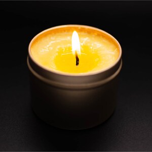 以下が含まれることがあります： 金属製の缶に入っている、黄色いワックスのプールと白い芯を持つ点火されたろうそく