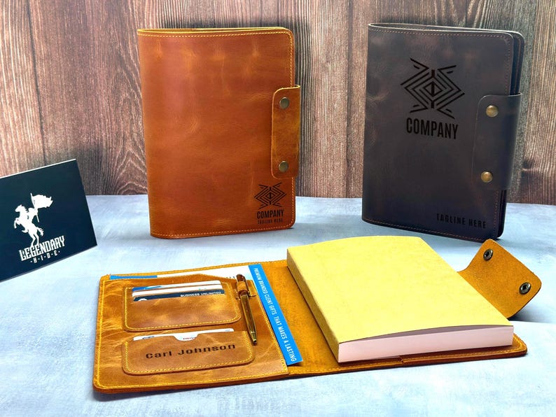 Peut inclure: Deux prot&egrave;ge-carnets en cuir, l'un beige et l'autre marron fonc&eacute;, dot&eacute;s d'une fermeture &agrave; pression et d'un logo g&eacute;om&eacute;trique. Un prot&egrave;ge-carnet ouvert pr&eacute;sente un bloc-notes jaune, un stylo et des fentes pour cartes avec le nom Carl Johnson.