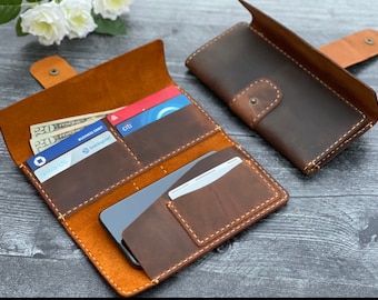May include: A brown leather wallet with multiple card slots and a phone pocket. The wallet is open and has several cards and cash inside.