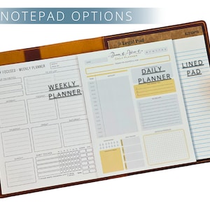 May include: A leather notepad with various paper inserts. The notepad includes a weekly planner, a daily planner, and a lined pad. The text "NOTEPAD OPTIONS", "WEEKLY PLANNER", and "DAILY PLANNER" are visible.