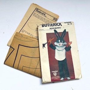 May include: Vintage Butterick sewing pattern for a Bugs Bunny costume. The pattern envelope features a Bugs Bunny illustration holding a carrot. Includes pattern pieces and instructions. The envelope is slightly worn.
