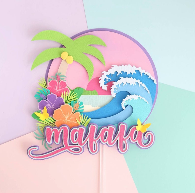 May include: A pink, blue, and green paper cake topper with a palm tree, waves, flowers, and the name "maiafa" in pink lettering.