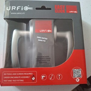 May include: A door handle set in a clear plastic package with a red and black cardboard sleeve. The brand name "URFIC" is visible. The text "EASY CLICK" and "FIRE RATED 30/60 FD" are also displayed. The package includes the text "NO TOOLS AND SCREWS REQUIRED".