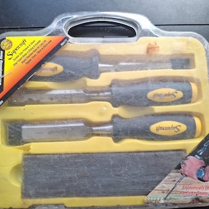 May include: A Supercraft power grip chisel set with a sharpening stone. The set includes three chisels with black and yellow handles and a sharpening stone, all in a clear plastic case.