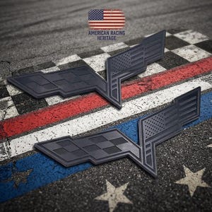 May include: Two matte black automotive emblems featuring a stylized checkered flag and a United States flag design. The emblems are positioned on a textured surface with a racing-themed graphic. The text AMERICAN RACING HERITAGE is visible.