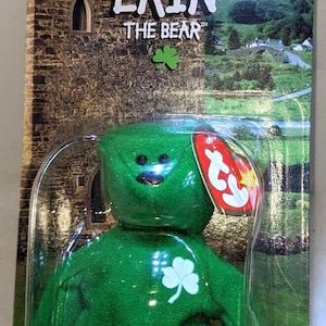 May include: A bright green plush bear named Erin the Bear in original packaging. The bear features a white shamrock on its chest and a red heart-shaped Ty tag. The backing card displays a stone castle, a rainbow, and Ronald McDonald House Charities logo.