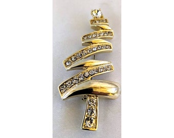 Puede incluir: Un broche de árbol de Navidad de tono dorado con diamantes de imitación transparentes. El árbol está hecho de una serie de líneas curvas y está decorado con una fila de diamantes de imitación en cada línea.