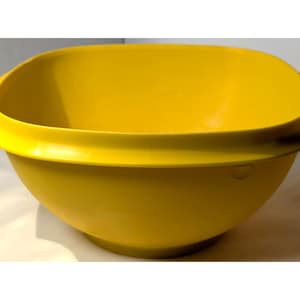 May include: A bright yellow plastic mixing bowl with a square shape and rounded corners. The bowl has a wide rim and two small handles on either side. This kitchenware item is ideal for mixing ingredients.