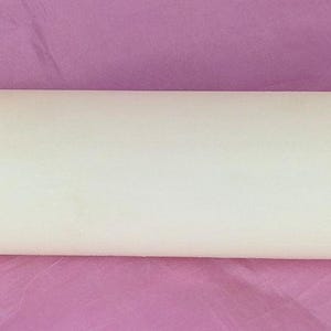 May include: A cream-colored rolling pin with a cylindrical body and ridged handles. The rolling pin is made of a solid material and is designed for use in baking and cooking. The handles are slightly flared for grip.