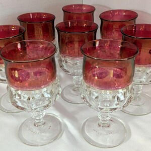 Puede incluir: Un conjunto de siete copas con un cuenco superior de vidrio rojo intenso y una base de vidrio transparente texturizado con un patrón facetado. Cada copa tiene un borde liso y redondeado y un pie circular resistente.