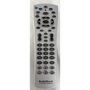 May include: Silver RadioShack 5-in-1 remote control with numerous buttons for various functions. Features buttons for power, volume, channel selection, and playback controls. The remote has a sleek, ergonomic design.