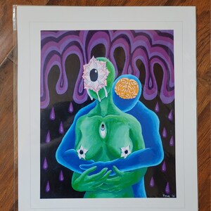 May include: An art print featuring two figures embracing, one green and one blue, with surreal elements. The green figure has an eye on its forehead and star-shaped nipples. The background is black with purple drips and rain. The print is in a white frame.