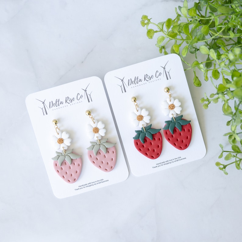 Handmade strawberry polymer clay earrings featuring vibrant red or pink berries with green leaves and white flower on top. Lightweight, hypoallergenic earrings perfect for summer outfits, fruit-themed accessories, and unique handmade gifts for her.