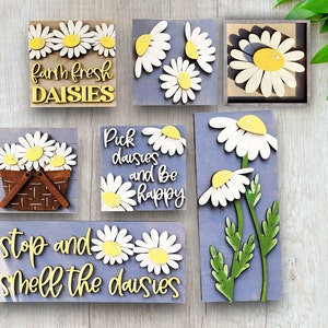 May include: Six wooden signs with daisy flower designs and text. The signs read "Farm Fresh Daisies", "Pick Daisies and Be Happy", "Stop and Smell the Daisies", and feature a daisy in a basket, a single daisy, and a bouquet of daisies.