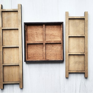 May include: Three wooden shelves with a black frame, each shelf has a square opening. The shelves are arranged vertically and are mounted on a white wall.