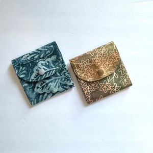 May include: Two small fabric pouches with button closures. One pouch is blue with a white floral pattern, the other is brown with a white floral pattern.