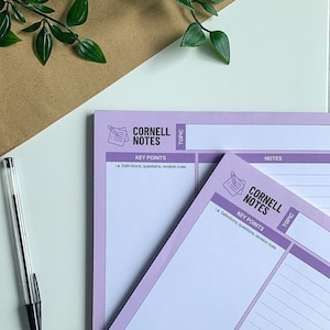 May include: Two purple Cornell Note-taking notebooks with lined pages and a section for key points. The text "Cornell Notes" is printed in white on the cover. The text "Key Points" is printed in black on the cover. The text "Le. Definitions, questions, revision cues" is printed in black on the cover.