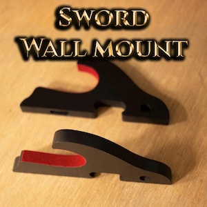 May include: Two black sword wall mounts with red felt inserts. The mounts are made of a solid material and are designed to hold a sword. The text "SWORD WALL MOUNT" is displayed in gold lettering.