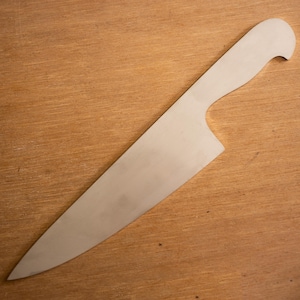 May include: A stainless steel chef's knife with a curved handle and a long, pointed blade. The knife is set against a wooden background, showcasing its polished metal finish and ergonomic design. This kitchen tool is designed for slicing and chopping.
