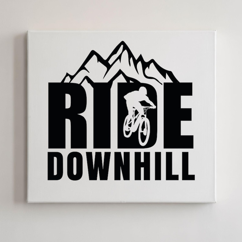 May include: A white canvas print featuring the words "RIDE DOWNHILL" in bold black letters. A silhouette of a mountain biker is integrated into the design, with a mountain range above the word "RIDE".