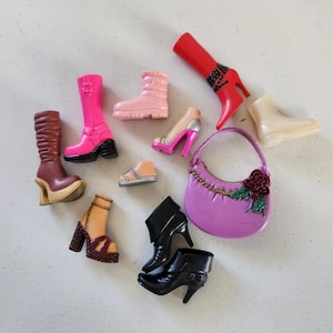 May include: A collection of miniature fashion accessories, including high-heeled boots and shoes in various colors like red, pink, and black. A small, purple handbag with a floral accent is also included.