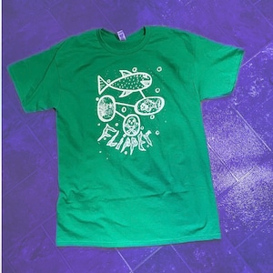 May include: Green t-shirt with a white graphic design of a fish, bubbles, and the word "FLIPPERS".