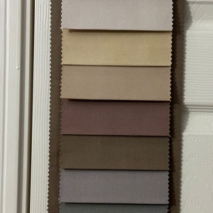 May include: A fabric swatch book with 14 different fabric samples. The samples are in various shades of beige, brown, pink, and blue.