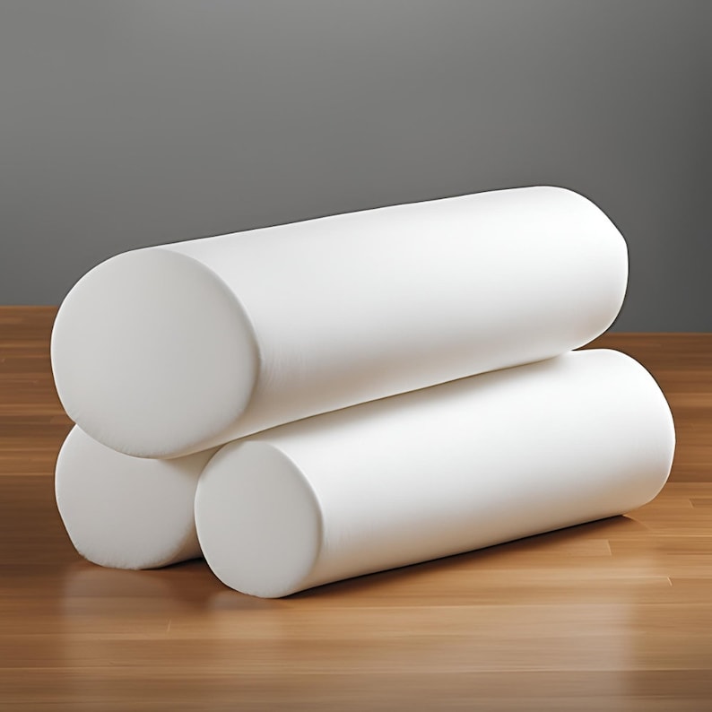 May include: Three white cylindrical foam rollers stacked on top of each other on a wooden surface.